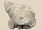 Pre-Columbian terracotta head fragment depicting a stylized human face with closed eyes and large ear ornaments.