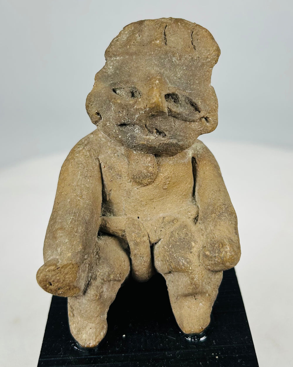 Ancient Pre-Columbian West Mexico seated male terracotta figure with projecting limbs and stylized facial features