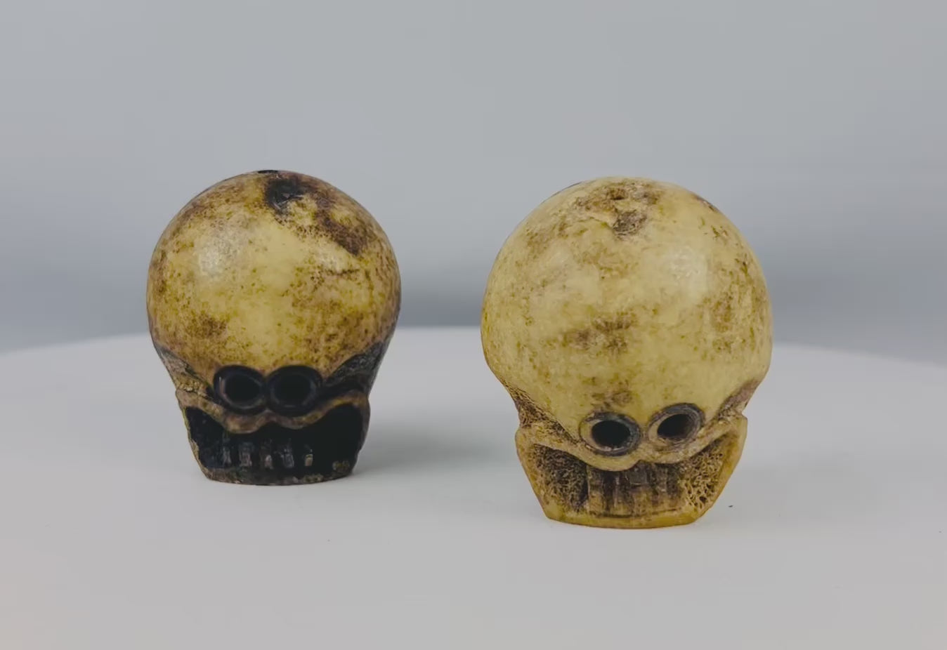 Pair of large 18th–19th century Tibetan Buddhist ritual beads carved from human femur bone, featuring intricate Citipati imagery, vertical suspension holes for stringing, fine patina, and devotional use in meditation on impermanence and mortality