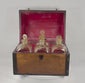 Video showing an early 19th-century Georgian mahogany boxed decanter set with brass handles, fitted interior compartments, four parcel-gilded square glass spirit decanters with stoppers, and detailed views of the historic wooden case.
