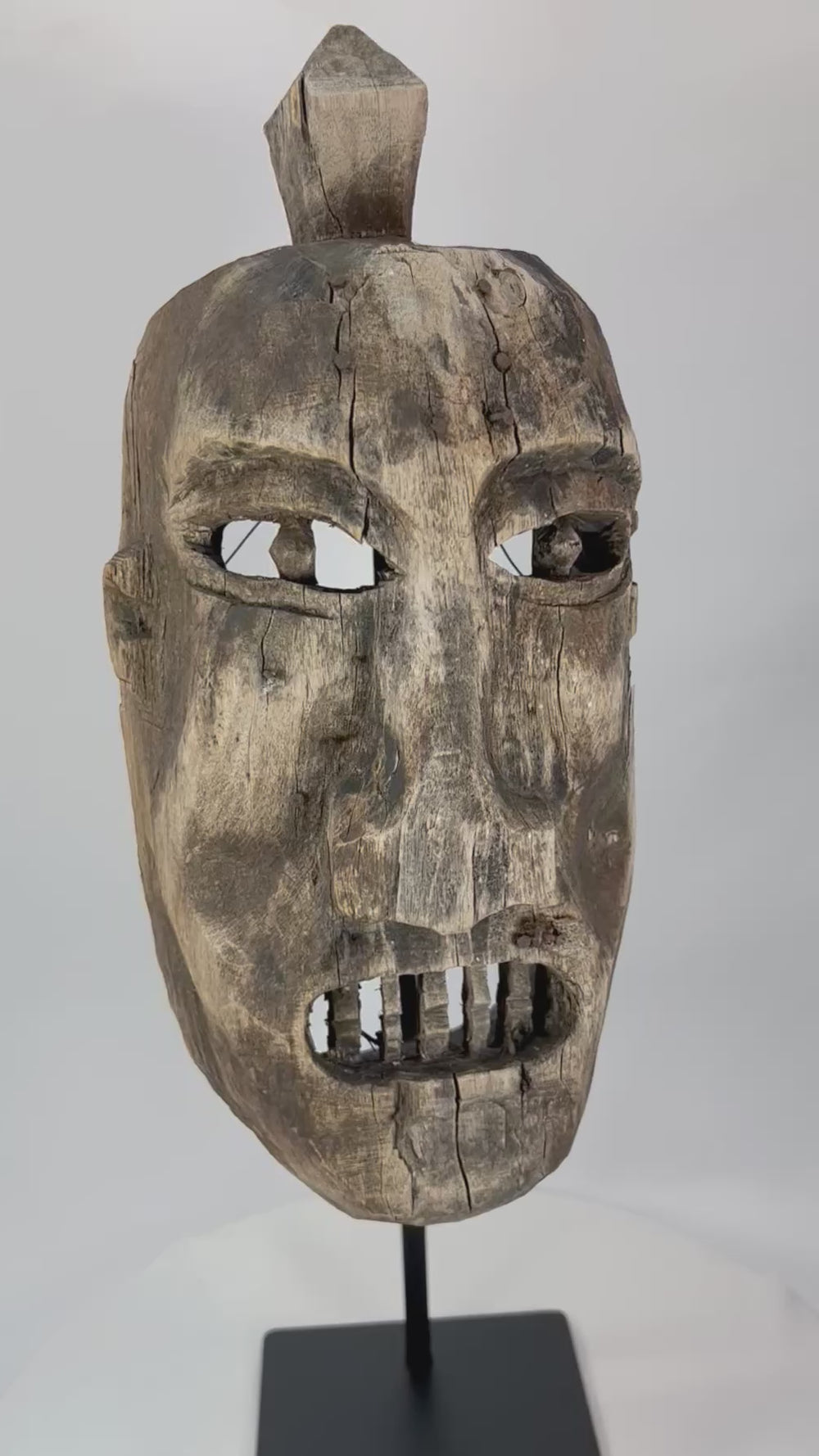 Full 360° spin of an aged tribal wooden mask showing carved eyes, teeth, and surface cracks