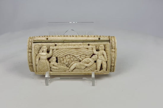 Front view of a Napoleonic POW carved bone snuff box displayed on a clear stand, showing detailed relief figures on a white background.