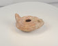 Rotating view of a Late Roman to Early Byzantine mold-made terracotta oil lamp with a central filling aperture, separate wick opening, raised nozzle channel, radiating decoration, solid rear handle, concentric base rings, and burial encrustation