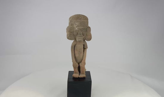 Mesoamerican Classic Period terracotta figure from Teotihuacan sphere with tall cylindrical headdress, incised roundels and step-fret band, large disk earspools, hands-on-knees posture, buff/orange clay with mineral accretions, mounted on modern black wood block, ca. 250–600 CE.