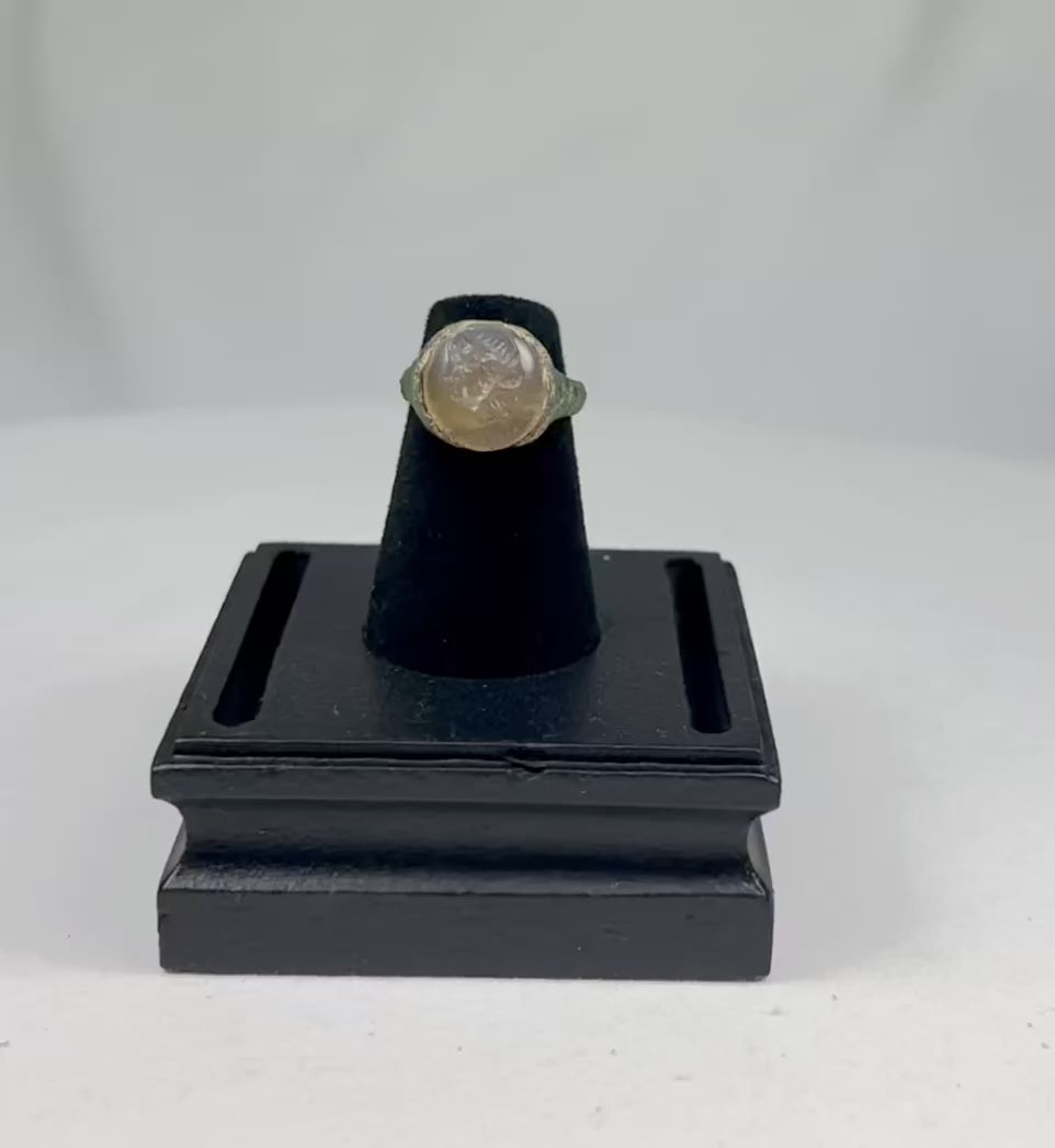 Ancient Indo-Greek ring from modern Afghanistan, Pakistan, or Northern India, circa 2nd–1st Century BCE, featuring a carved garnet bezel depicting a bearded male bust in profile. The metal band shows natural patina, reflecting over 2,000 years of history and the Hellenistic-Indian artistic fusion of the Indo-Greek Kingdom.