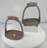 Rotating view of a pair of antique Chinese hand-forged iron stirrups with broad pierced footplates, suspension loops, decorative chiseled details, and aged patina