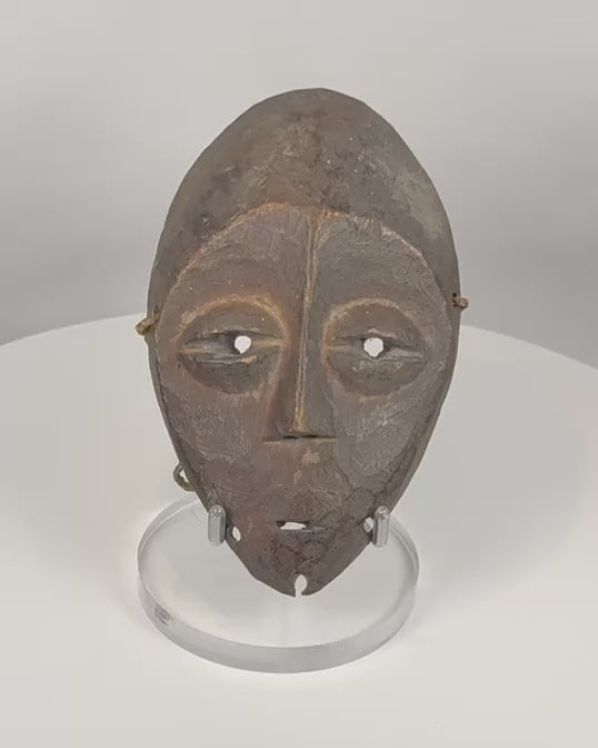 360-degree view of an authentic Lega passport mask carved from wood with dark ritual patina, elongated facial features, and original suspension holes, Democratic Republic of the Congo, mid-20th century.