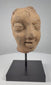 Video showcasing an ancient Indian Gupta-period terracotta head fragment dating to the 3rd–5th century CE, highlighting its almond-shaped eyes, arched brows, serene facial expression, weathered clay surface, mineral accretions, and modern display stand.