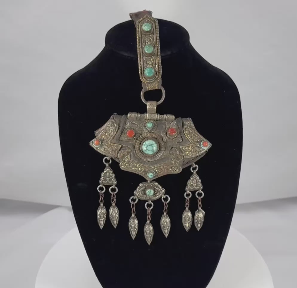 360-degree video of an antique Tibetan Himalayan gau portable shrine pendant showcasing the repoussé silvered copper alloy, turquoise and coral cabochons, articulated pendant drops, original textile suspension, and intricate decorative details.