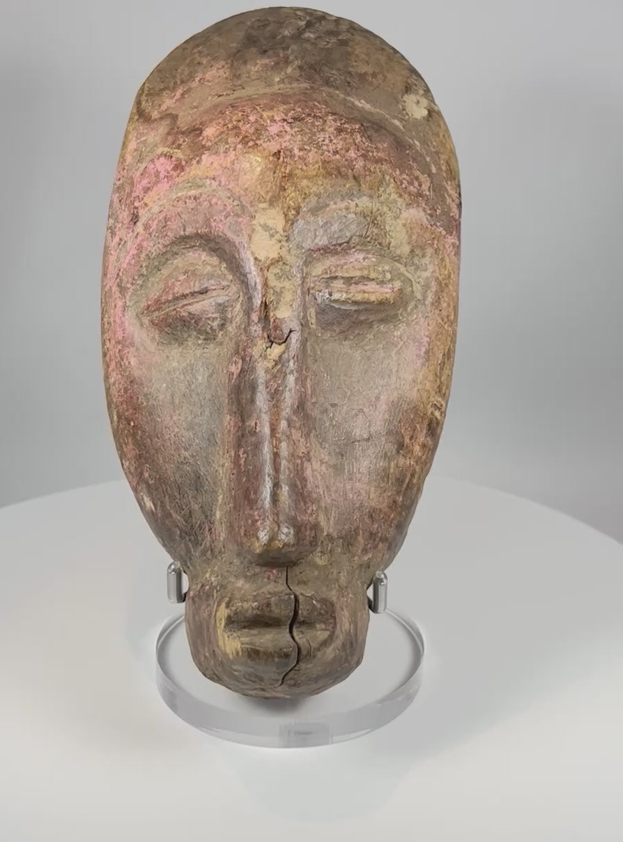 Video showcasing West African wooden mask with carved facial features pigment traces and aged patina from multiple angles