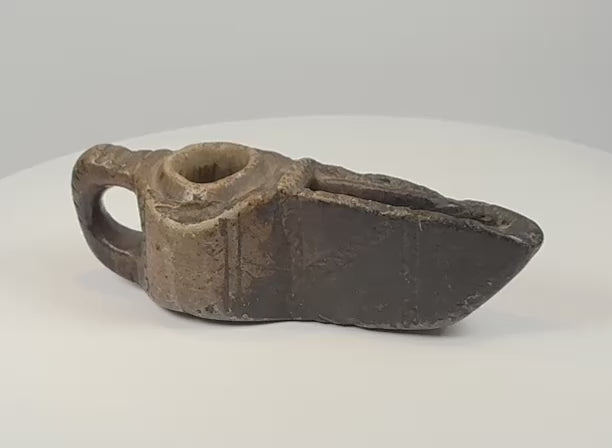 Rotating 360-degree video of an early Islamic carved stone oil lamp, showing its geometric decoration, wick spout, stone construction, and aged patina.