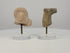 360-degree rotating view of two ancient terracotta artifacts: a Roman female bust featuring an elaborate Flavian-style curled hairstyle and detailed facial features, alongside a Mesopotamian bovine protome depicting a stylized bull's head and neck. Both fragments display weathered surfaces, age-related wear, and distinctive craftsmanship, presented on individual clear acrylic display stands.