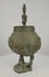 360-degree rotating video of an antique Dogon bronze ritual container from Mali, West Africa, circa 19th century, featuring a rounded vessel with engraved spiral and geometric motifs, three stylized anthropomorphic legs, and a sculpted human figure crowning the lid. The ceremonial vessel displays rich green verdigris patina, traditional Dogon metalworking craftsmanship, and age-related surface wear, shown from multiple angles.