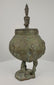 360-degree rotating video of an antique Dogon bronze ritual container from Mali, West Africa, circa 19th century, featuring a rounded vessel with engraved spiral and geometric motifs, three stylized anthropomorphic legs, and a sculpted human figure crowning the lid. The ceremonial vessel displays rich green verdigris patina, traditional Dogon metalworking craftsmanship, and age-related surface wear, shown from multiple angles.