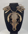 Video of an animal skull necklace on a black display bust, featuring a large central skull, two smaller skulls, curved teeth, and woven twine.