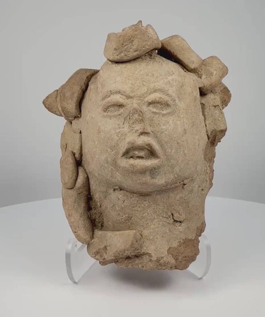 Video showcasing an ancient Pre-Columbian Mesoamerican terracotta head dating to circa 1000–1500 CE, highlighting its elaborate headdress, half-closed eyes, slightly open mouth, hand-formed clay construction, and naturally aged earthen patina.