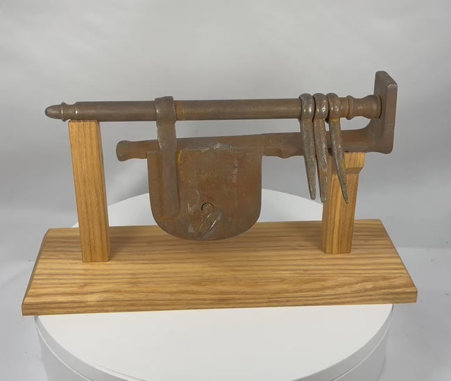 Rotating presentation of an antique European wrought-iron sliding hasp gate lock with key, mounting staples, and custom display stand