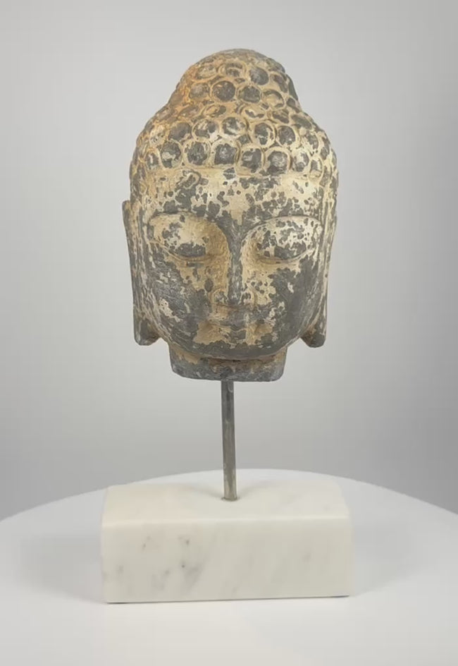 Video showing multiple angles of an 18th–19th century Southeast Asian carved stone Buddha head with curled hair, traces of pigment and a modern marble display base