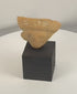 Rotating view of a Pre-Columbian terracotta human head fragment with circular earspools, traces of white pigment, and archaeological surface patina, mounted on a custom display stand.