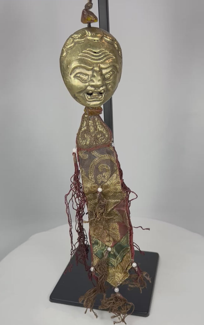 360-degree view of Tibetan gilt bronze guardian mask pendant with textile tassels and bead elements
