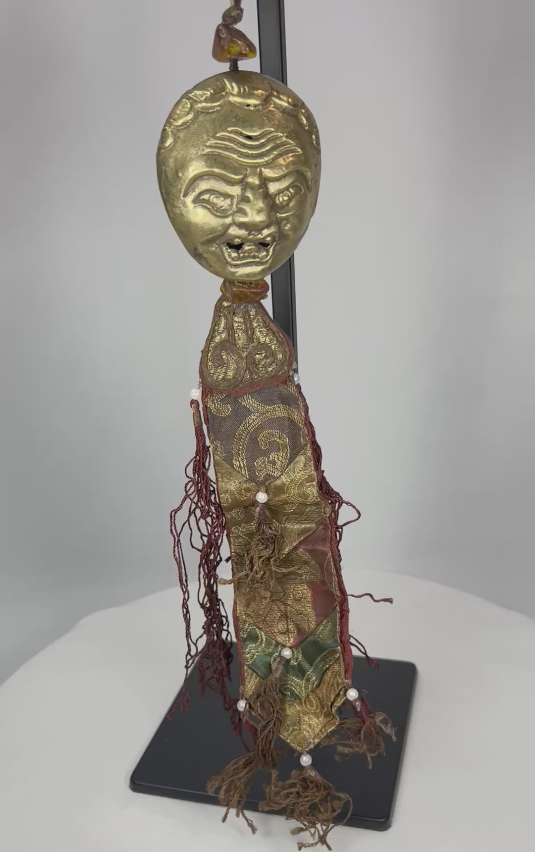 360-degree view of Tibetan gilt bronze guardian mask pendant with textile tassels and bead elements