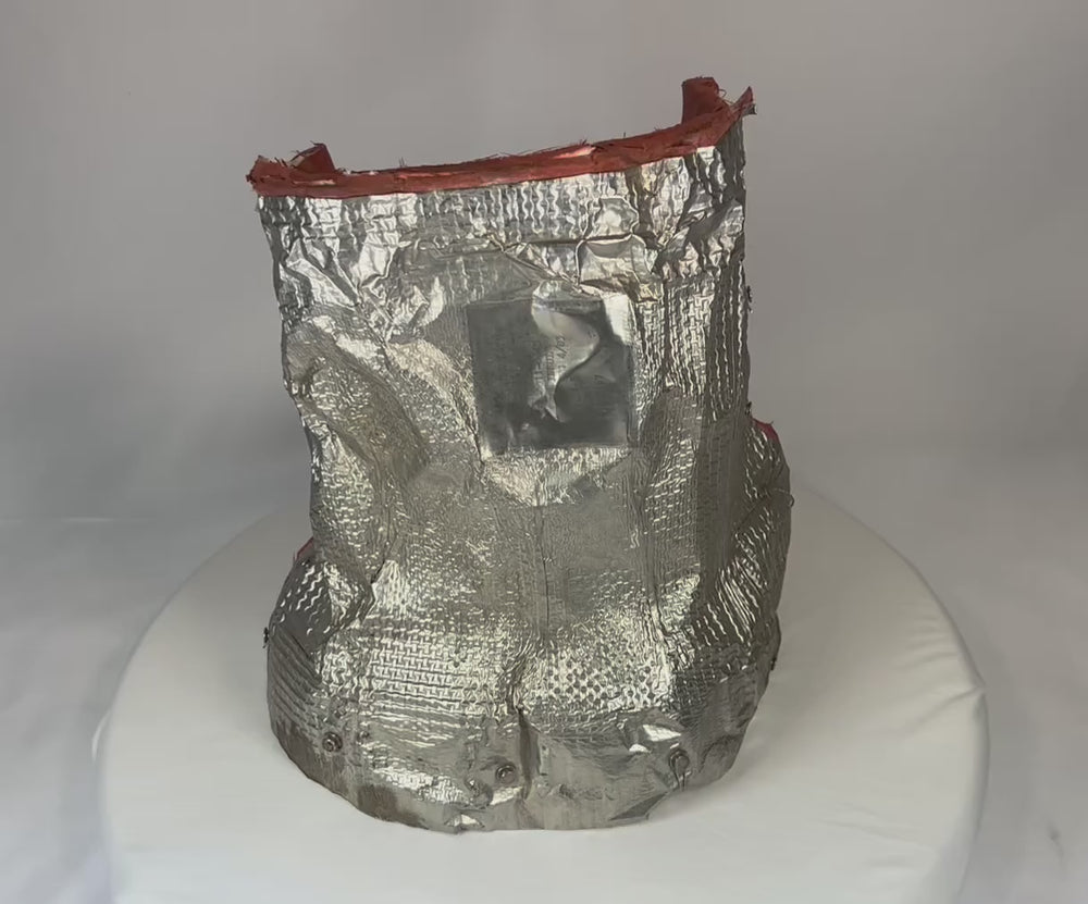 Flown NASA Space Shuttle blanket insulation artifact made of fibrous silica batting, stamped April 1983 with serial number and manufacturer code. Used in the orbiter’s Thermal Protection System (TPS) for pitch actuator thermal shielding, approximately 11 x 10 inches.