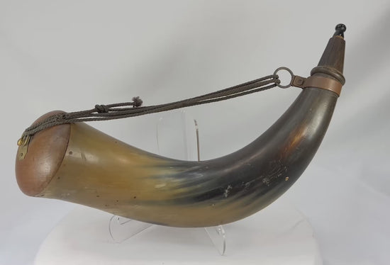 60-degree rotating view of an antique black powder horn from circa 1780–1830, showing polished horn body, wooden fittings, brass mount, and attached carry cord.