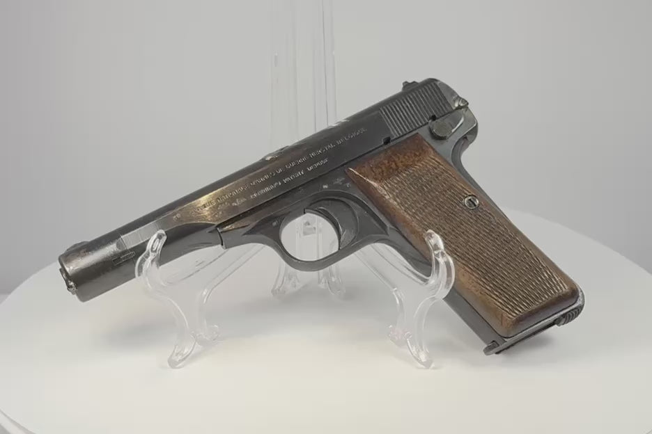 Video of a deactivated WWII FN Browning Model 1922 on a clear display stand, showing worn blued steel and checkered walnut grips.