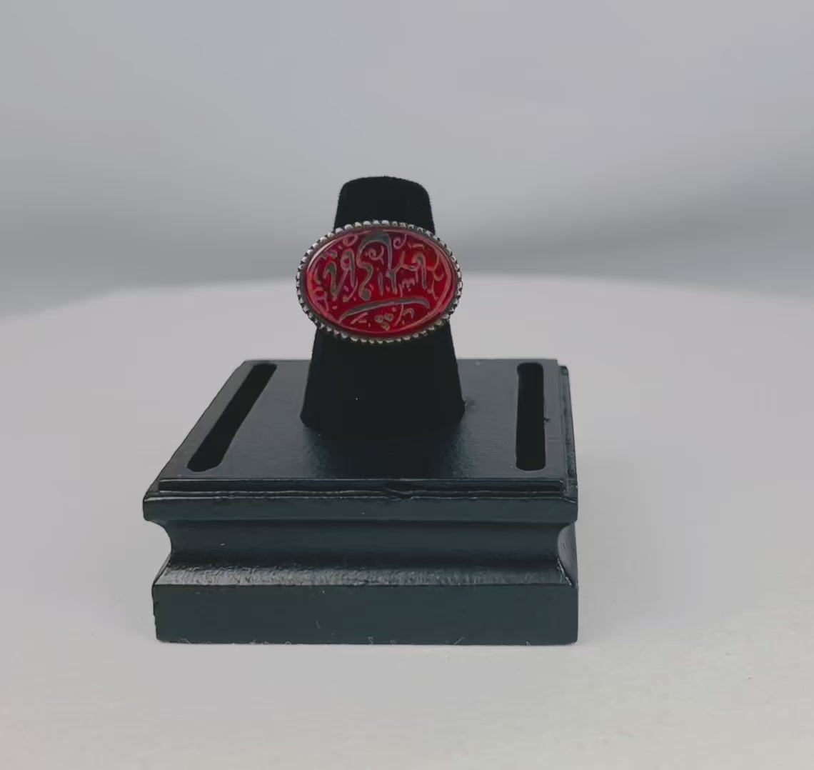 Oval carnelian intaglio ring from the Ancient Near East, 1st millennium BCE. Features engraved animal and symbolic motifs on red carnelian, set in a silver bezel, displayed on a black stand. Excellent condition with finely detailed intaglio carvings.