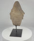 Rotating view of an antique African carved stone head fragment on a custom black metal stand, showing its conical headdress, stylized facial features, weathered surface, mineral deposits, and fragmentary sculptural form.