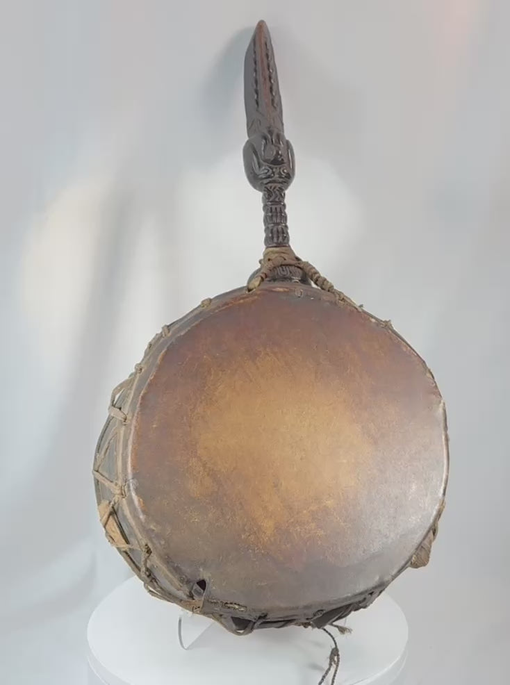 360-degree rotating view of an antique Nepalese Dhyāngro shaman's drum featuring carved hardwood construction, stretched hide drumheads, extensive rawhide lacing, and its original curved wooden striker. Traditional Himalayan ritual instrument used by Jhankri shamans in healing, trance, and spiritual ceremonies.