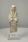 360-degree view of an Egyptian limestone ushabti figure displayed on a clear acrylic stand, showing its long wig, folded arms, worn hieroglyphic inscription, and weathered cream-coloured surface.