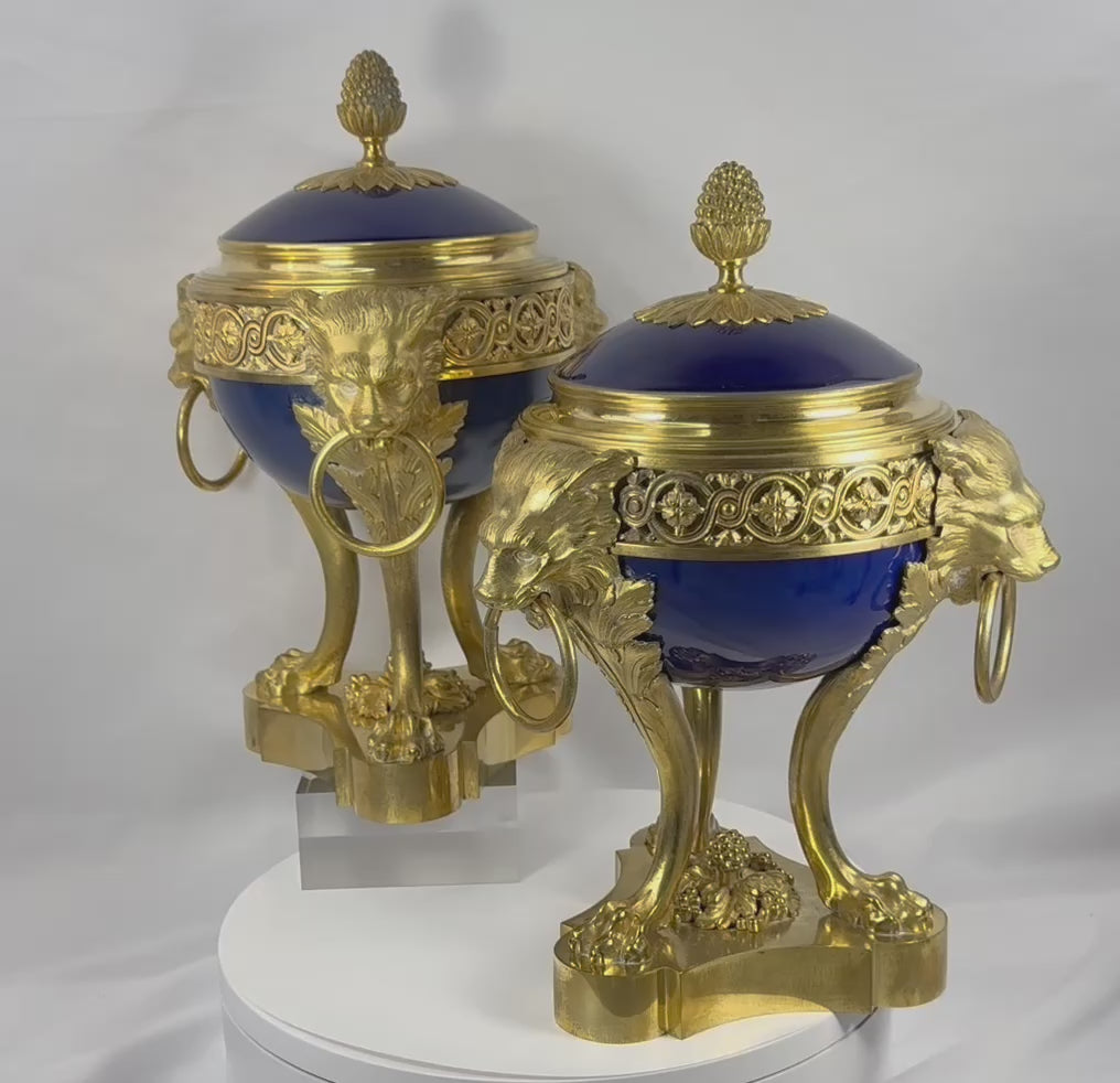 360-degree video of a pair of Louis XVI Revival covered vases featuring cobalt-blue porcelain bodies, gilt bronze ormolu mounts, lion mask ring handles, openwork galleries, pinecone finials, and finely cast lion-form legs in the manner of Sèvres porcelain.
