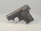 Deactivated FN Browning Model 1906 pocket pistol on a display stand, showing worn blued steel and checkered FN-monogram grips.