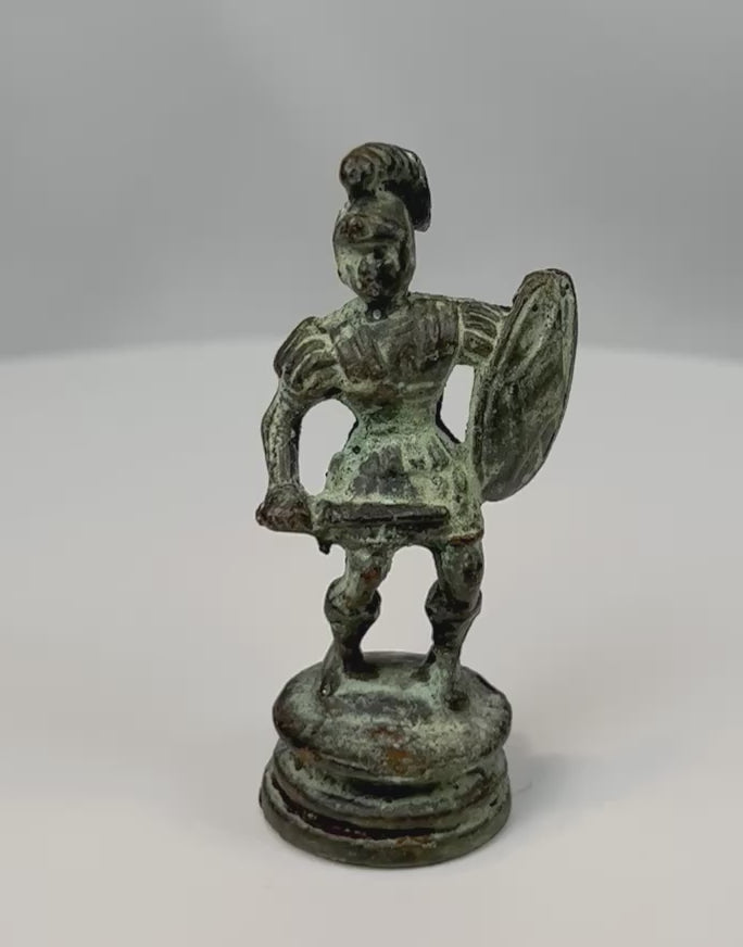 360° rotating view of an antique bronze classical warrior figure with helmet, shield, and aged green patina