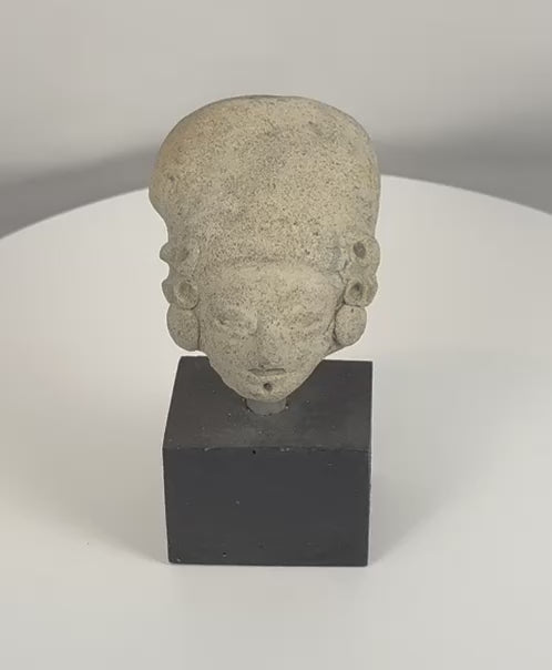 Rotating view of a Pre-Columbian terracotta effigy head from West Mexico, highlighting the elongated cranial form, prominent ear spools, stylized facial features, archaeological weathering, and ancient surface patina from multiple angles.