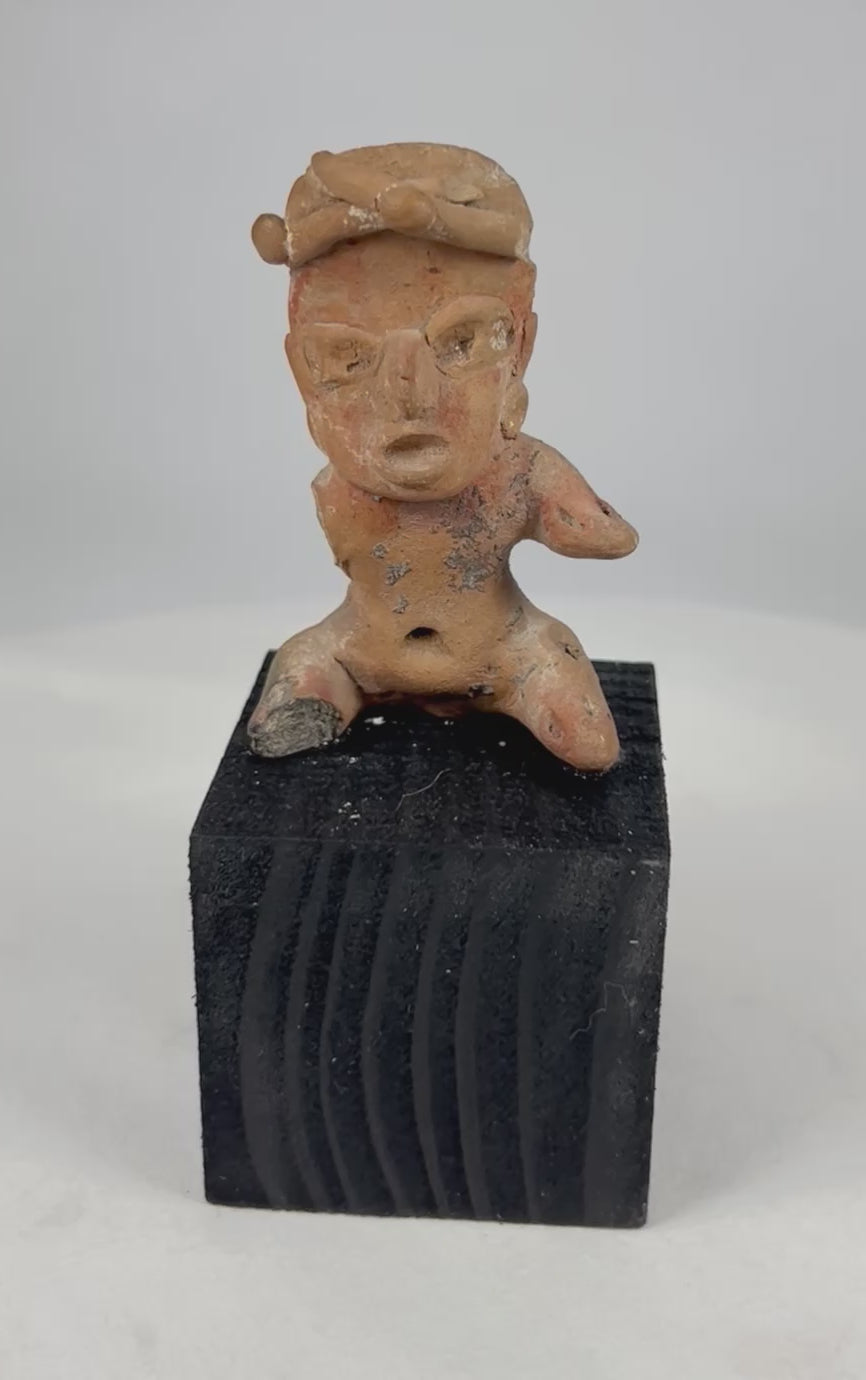 360-degree video of an ancient Pre-Columbian West Mexico seated terracotta figure showing expressive facial details, headdress, pierced ears, pigment remains, and archaeological patina