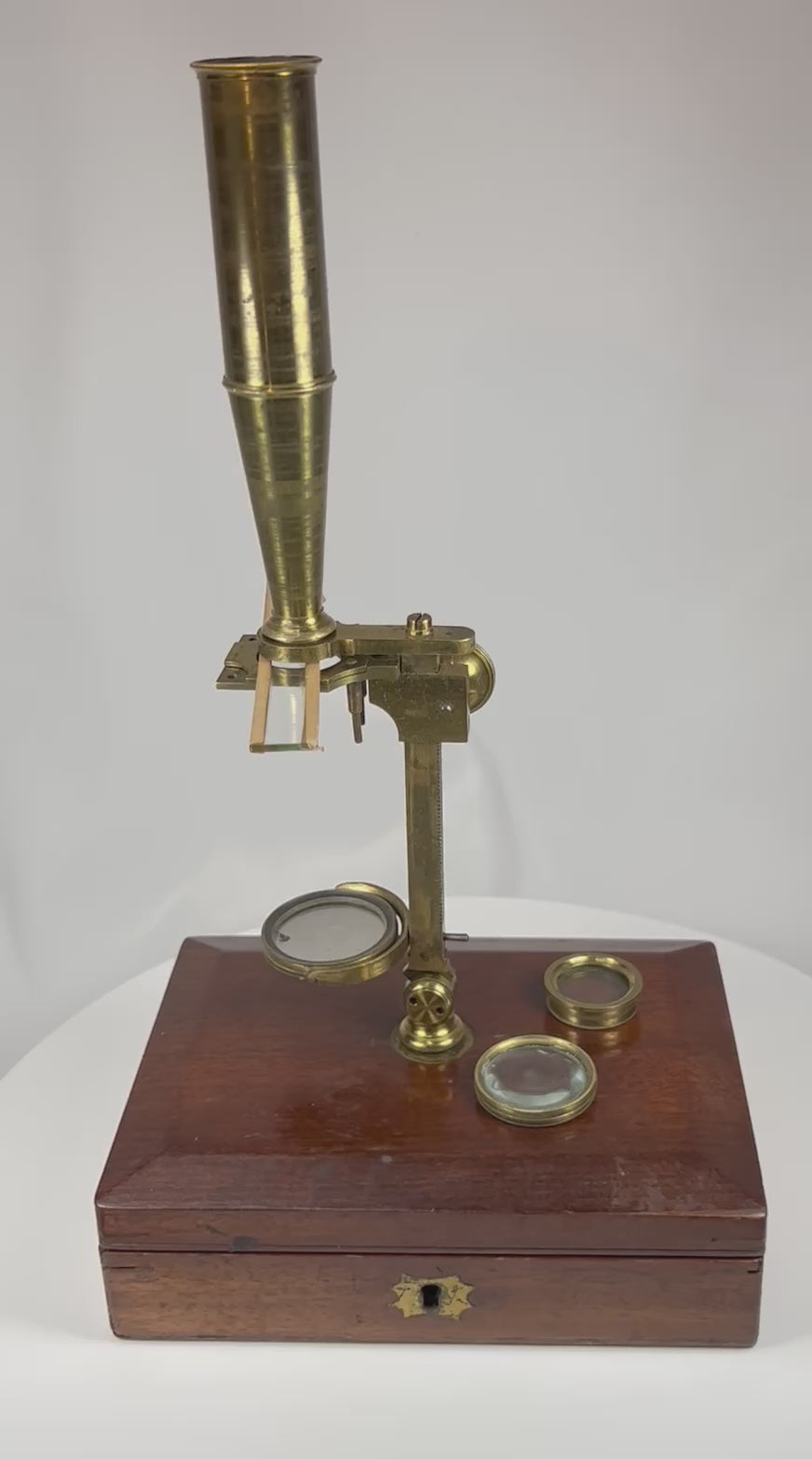 360 degree view of a Victorian brass Gould type simple microscope with interchangeable lenses and original mahogany storage case.
