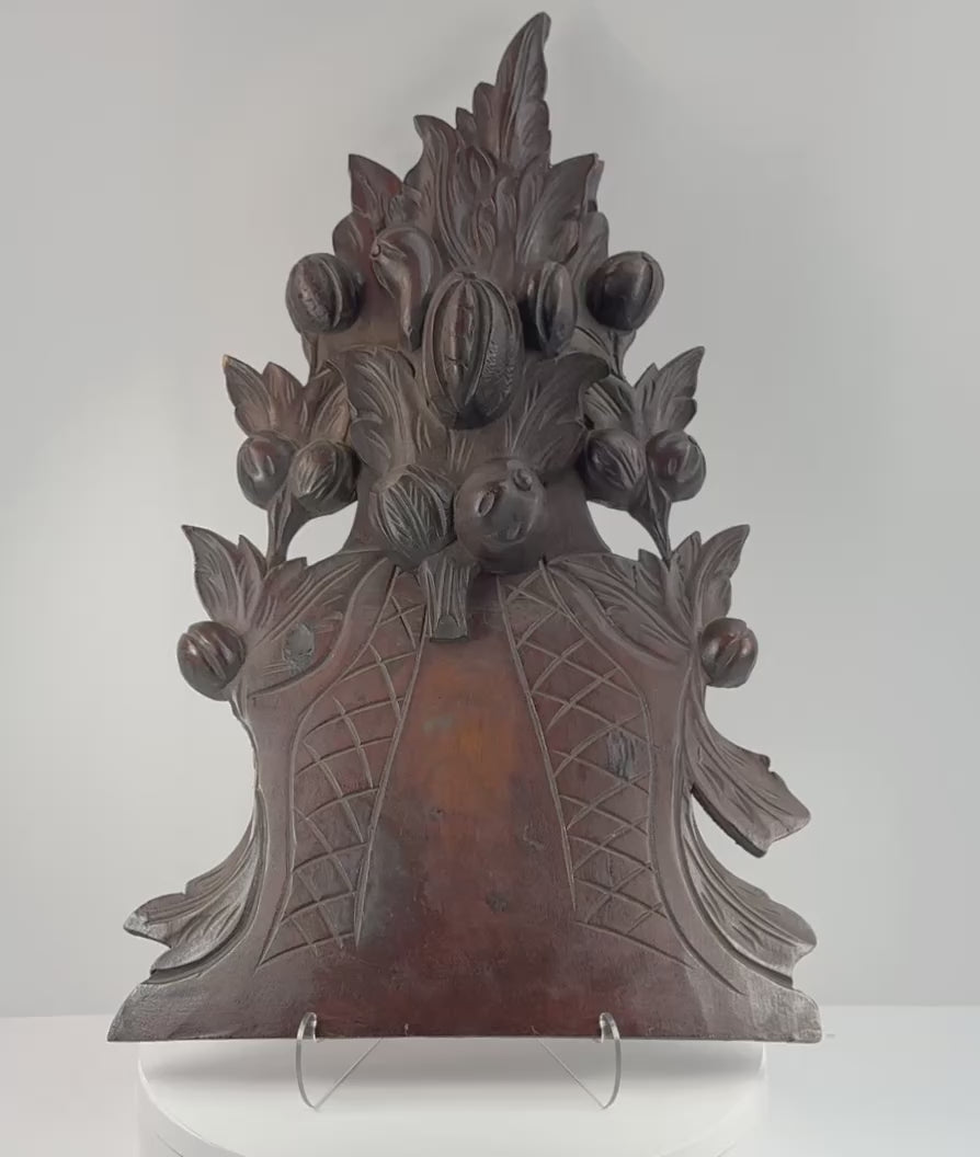Antique Black Forest-style carved wood furniture crest shown in detail, highlighting the fruit basket, foliage, pierced carving, aged patina, mounting points and historic repairs.