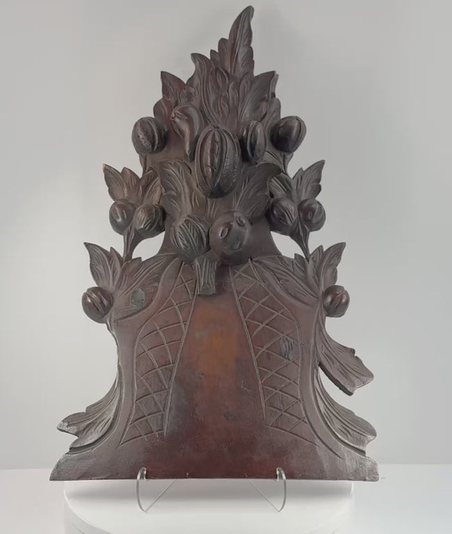 Antique Black Forest-style carved wood furniture crest shown in detail, highlighting the fruit basket, foliage, pierced carving, aged patina, mounting points and historic repairs.