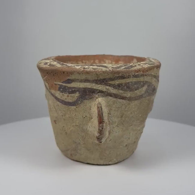 Ancient Afghan terracotta mortar dating to the 12th century CE during the Islamic Golden Age, featuring decorative black slip motifs around the rim, projecting side handles, a rounded grinding compartment, natural interior abrasions, warm earthen patina, and traditional medieval Islamic pottery craftsmanship.