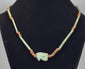 360-degree rotating view of an ancient Egyptian-style faience necklace featuring a turquoise-green Eye of Horus (Wedjat) amulet, elongated tubular beads, and earthy brown disc-shaped spacers. The video highlights the protective eye symbol, aged surfaces, intricate bead arrangement, and distinctive blue-green coloration from multiple angles.