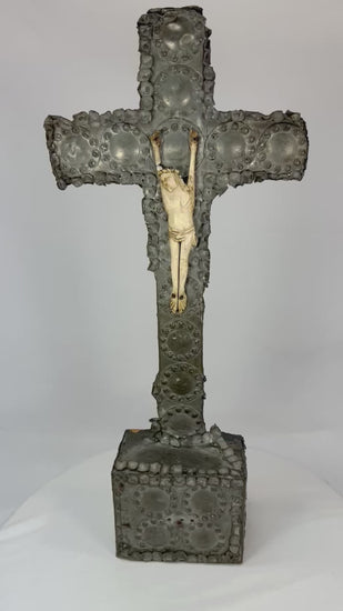360° view of an antique hand-carved crucifix featuring a bone corpus on a repoussé-decorated wooden cross with aged patina, displayed under soft lighting on a white background.