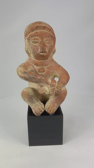 Pre-Columbian seated terracotta figure from West Mexico (Nayarit/Jalisco), circa 300 BCE–300 CE, hand-molded with red slip, stylized anthropomorphic features, burnished surface, shaft tomb funerary artifact on black display stand
