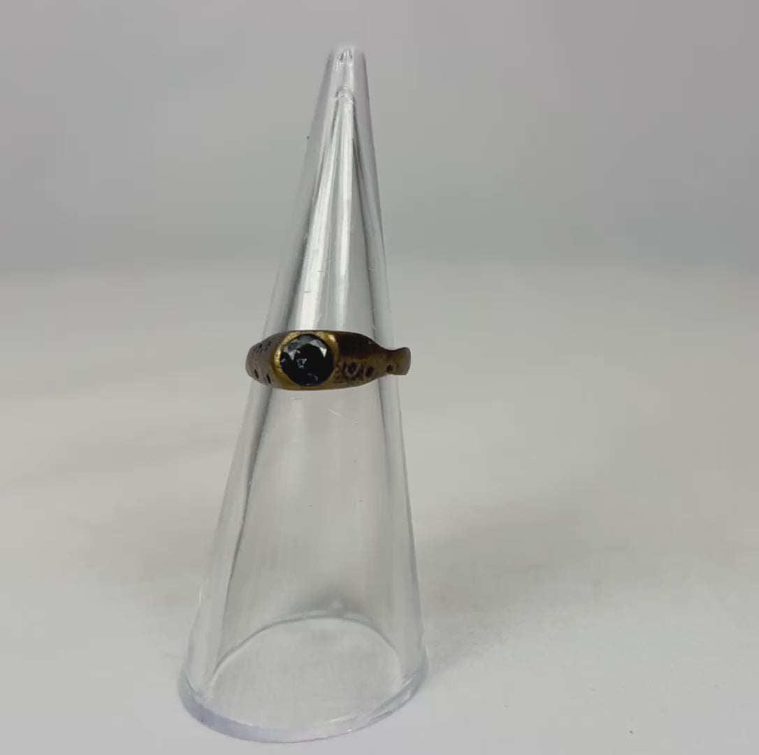 360-degree view of an ancient brass ring rotating on a clear display cone