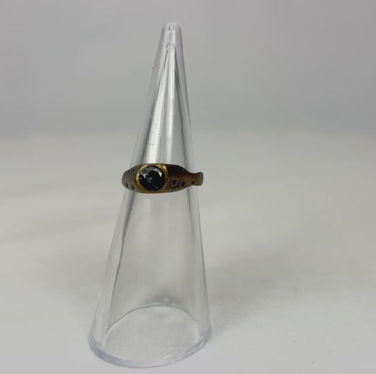 360-degree view of an ancient brass ring rotating on a clear display cone