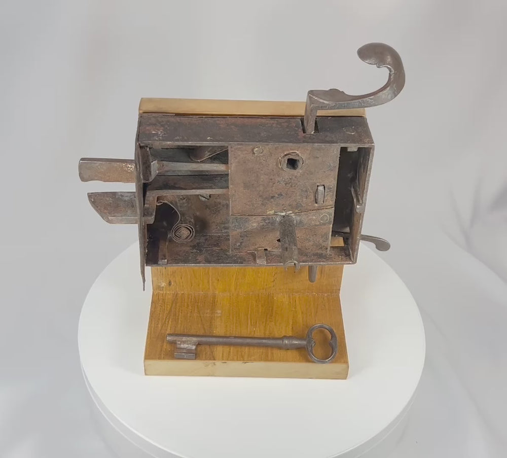 360° rotating view of a 19th century iron door lock mechanism with exposed internal components and multi-bolt system