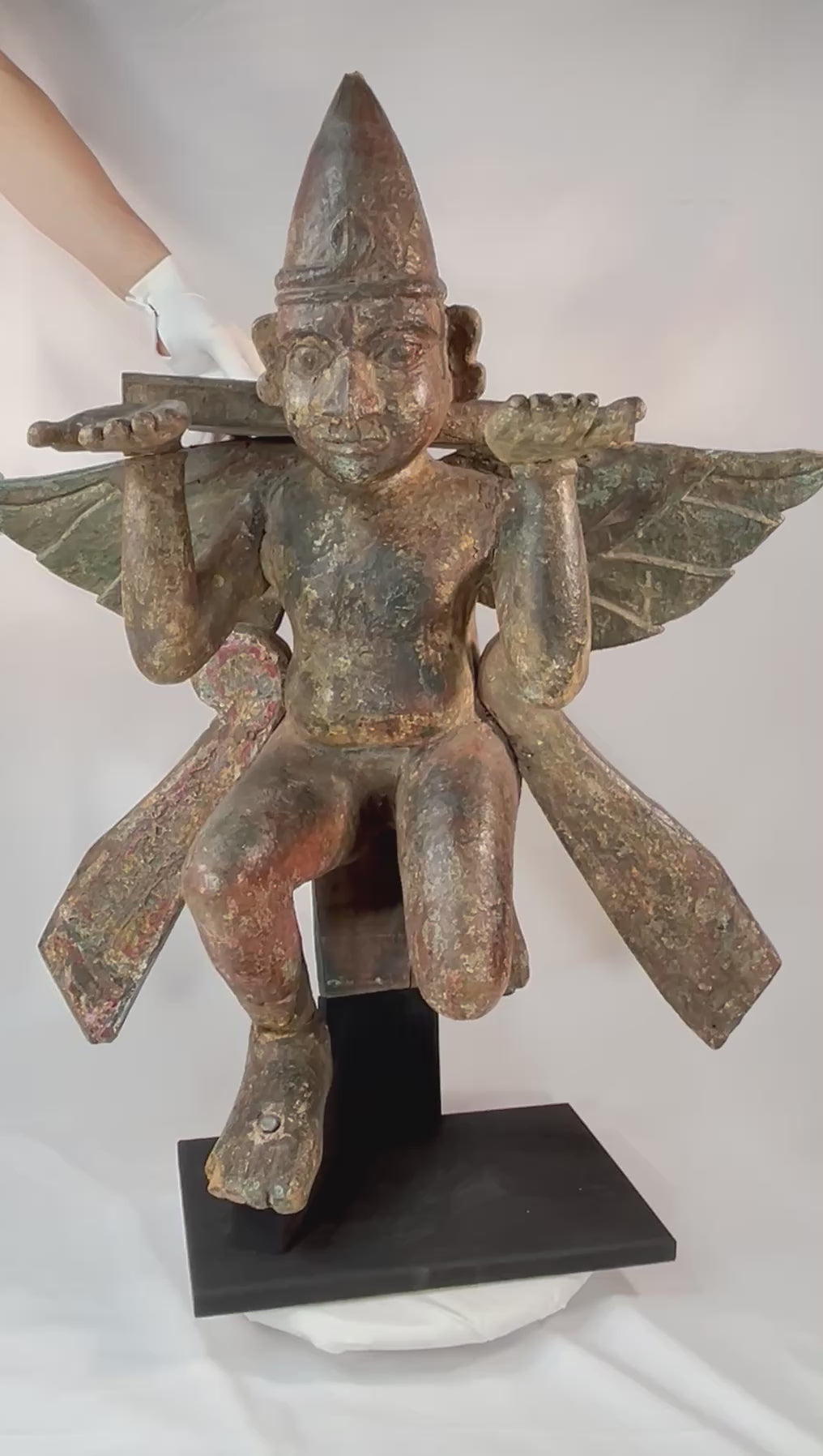 360° video of an antique hand-carved wooden winged temple guardian figure on a black museum stand, circa 18th–19th century.