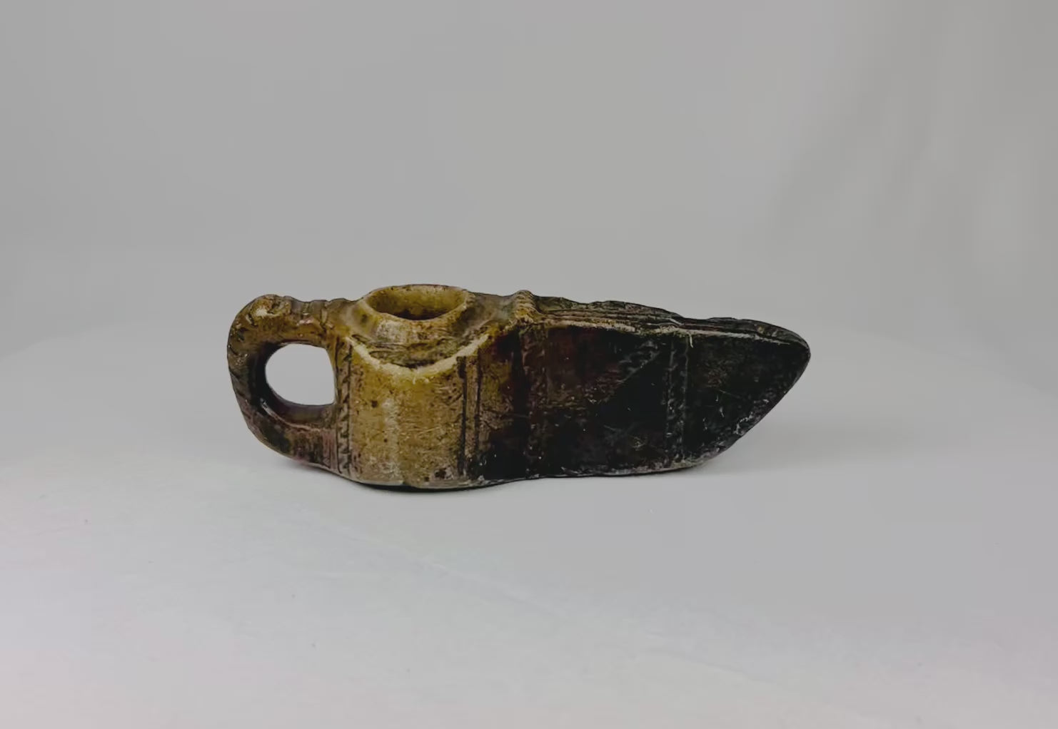 Ancient Islamic stone oil lamp from the early Islamic period (circa 7th–12th century CE). Hand-carved with geometric incised decoration, open spout for a wick, and natural patina. Reflects early Islamic artistry, domestic and ceremonial use, and cultural emphasis on geometric design and spiritual symbolism.