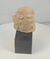Rotating view of an ancient Mesoamerican terracotta head fragment with heavily lidded eyes, circular ear ornaments, pigment traces, and a weathered archaeological surface